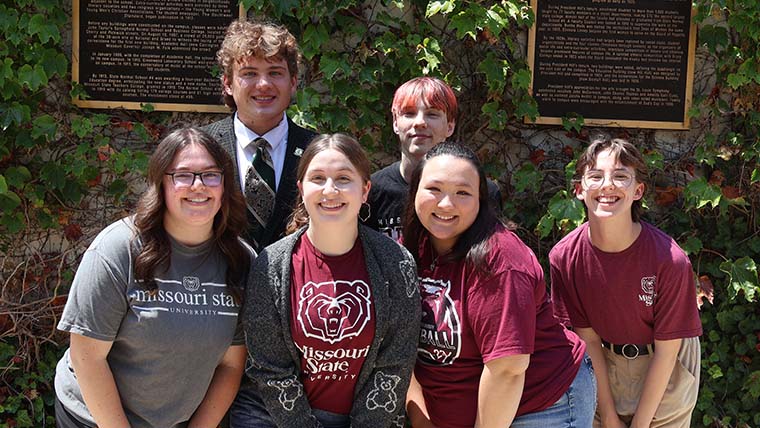 RHA Executive Board members standing around a maroon bear statue.